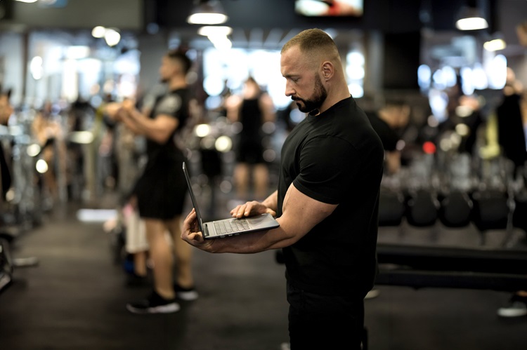 trener personalny pracuje przy laptopie